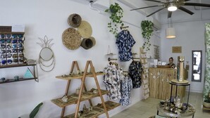 A boutique store with shelves of sunglasses, woven baskets, and hanging garments. - Experience historic charm near Kailua Pier - Walk to restaurants, shops,AC,Wifi (Kailua-Kona)