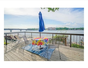 Enjoy a serene riverside retreat with a deck offering a bridge view, comfortable seating, and a shaded area.