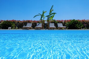 A clear blue pool with three lounge chairs and a palm tree in the center. - Villa in Salento - Private Pool - 24/7 Support (Mesagne)