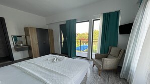 Et hotelværelse med seng, stol, skab, spejl og en balkon med udsigt.