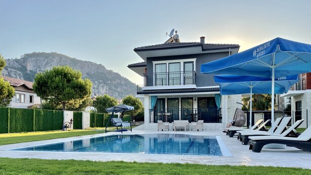 Et moderne hus med to etager, swimmingpool, udendørs siddepladser og udsigt til bjerge.