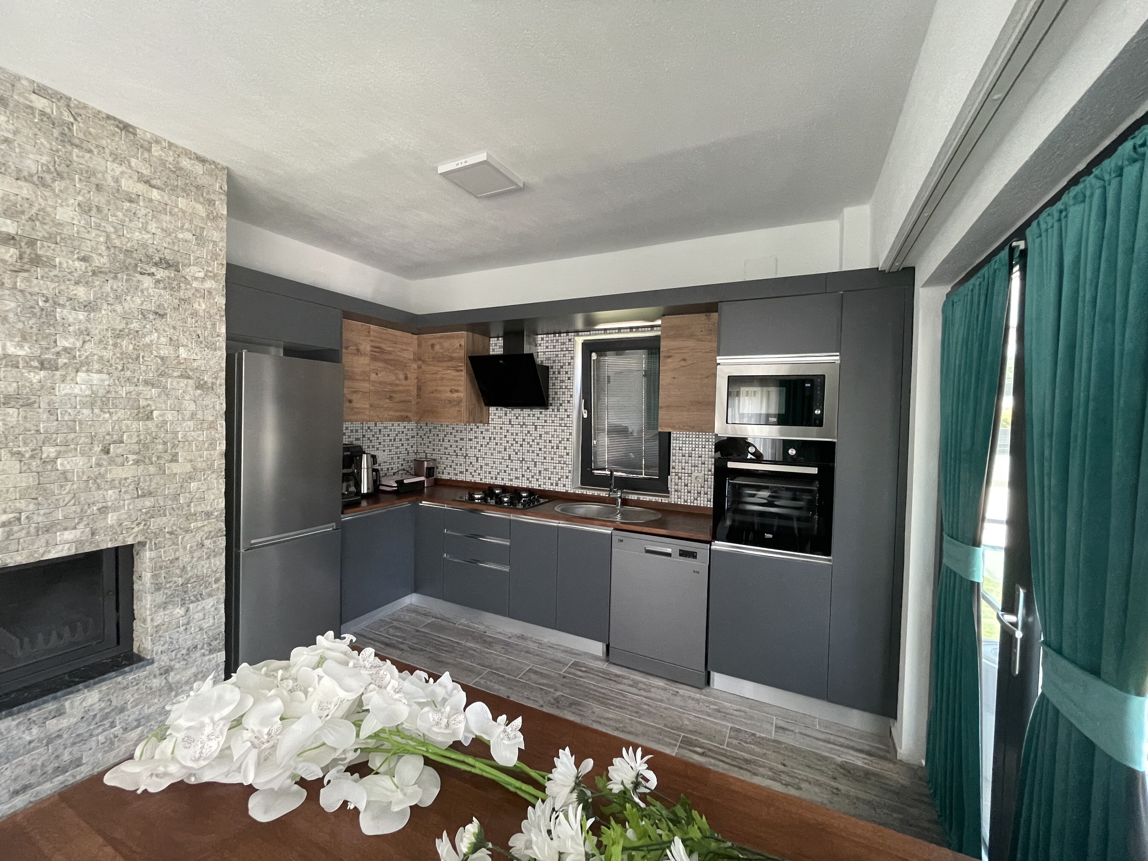 A modern kitchen with grey cabinets, a built-in oven, and a microwave.