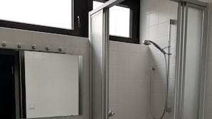 Un bany amb dutxa trencada, un lavabo i un vàter.