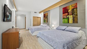 Quarto com duas camas, cômoda de madeira e um quadro na parede.