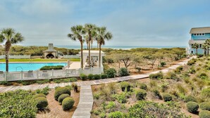 A pool area with a wooden deck, palm trees, and a view of the ocean. - Direct Beach/Pool Access from Watersound Condo - Comp Bikes, Boards, Beach Gear! (Watersound)