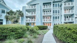 A multi-story hotel with a symmetrical facade, balconies, and a central walkway. - Direct Beach/Pool Access from Watersound Condo - Comp Bikes, Boards, Beach Gear! (Watersound)