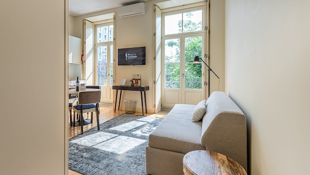 Ett modernt vardagsrum med en soffa, ett litet bord, en stol och en tv som hänger på väggen.