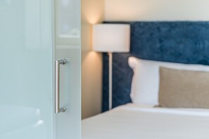 Una habitación de hotel con una cama, una lámpara de noche y una puerta.