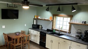 Uma cozinha compacta com armários de madeira, uma mesa de jantar e um forno embutido.