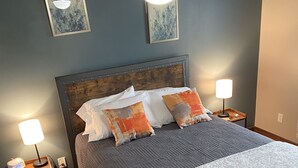 Quarto com uma cama grande, duas mesas de cabeceira com luminárias, um ventilador de teto e um tapete estampado.
