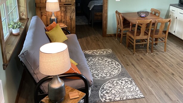 Uma sala de estar aconchegante com sofá, mesa de centro, televisão e mesa de jantar com cadeiras.