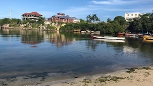 A calm river with boats, a house with a red roof, and a white building in the background. - Marvettes Hideaway (Lucea)