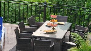 A patio with wicker furniture and a glass table set for dining. - Marvettes Hideaway (Lucea)