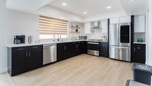 A modern kitchen with black cabinets, stainless steel appliances, and a wooden floor. - Shuffleboard/Swimming Pool/BBQ Grill, 4 Miles To The Strip, Pet Friendly! (Las Vegas)