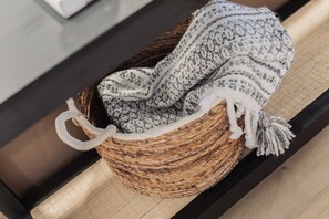 A woven basket with a crocheted blanket and a tassel, placed on a wooden surface. - Shuffleboard/Swimming Pool/BBQ Grill, 4 Miles To The Strip, Pet Friendly! (Las Vegas)