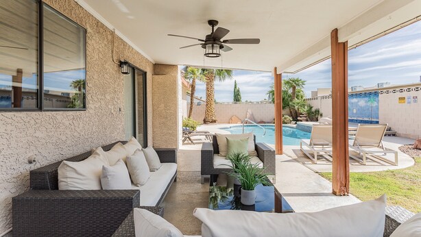 A covered outdoor seating area with a ceiling fan, a pool, and lounge chairs. - Shuffleboard/Swimming Pool/BBQ Grill, 4 Miles To The Strip, Pet Friendly! (Las Vegas)