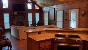 Interior acogedor de una cabaña con sala de estar, cocina y chimenea.