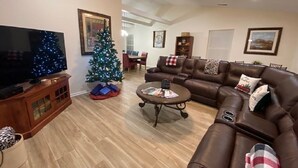 Un soggiorno con un divano in pelle marrone, un tavolino da caffè con riviste, un televisore e un albero di Natale.
