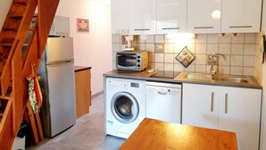 Una cocina compacta con lavadora, tostadora y lavamanos.