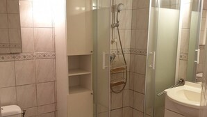 Un baño moderno con ducha de mampara de vidrio, inodoro y lavamanos.