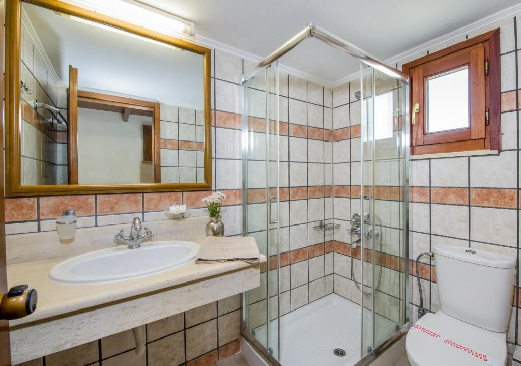 A bathroom with a glass-enclosed shower, a sink, and a toilet.