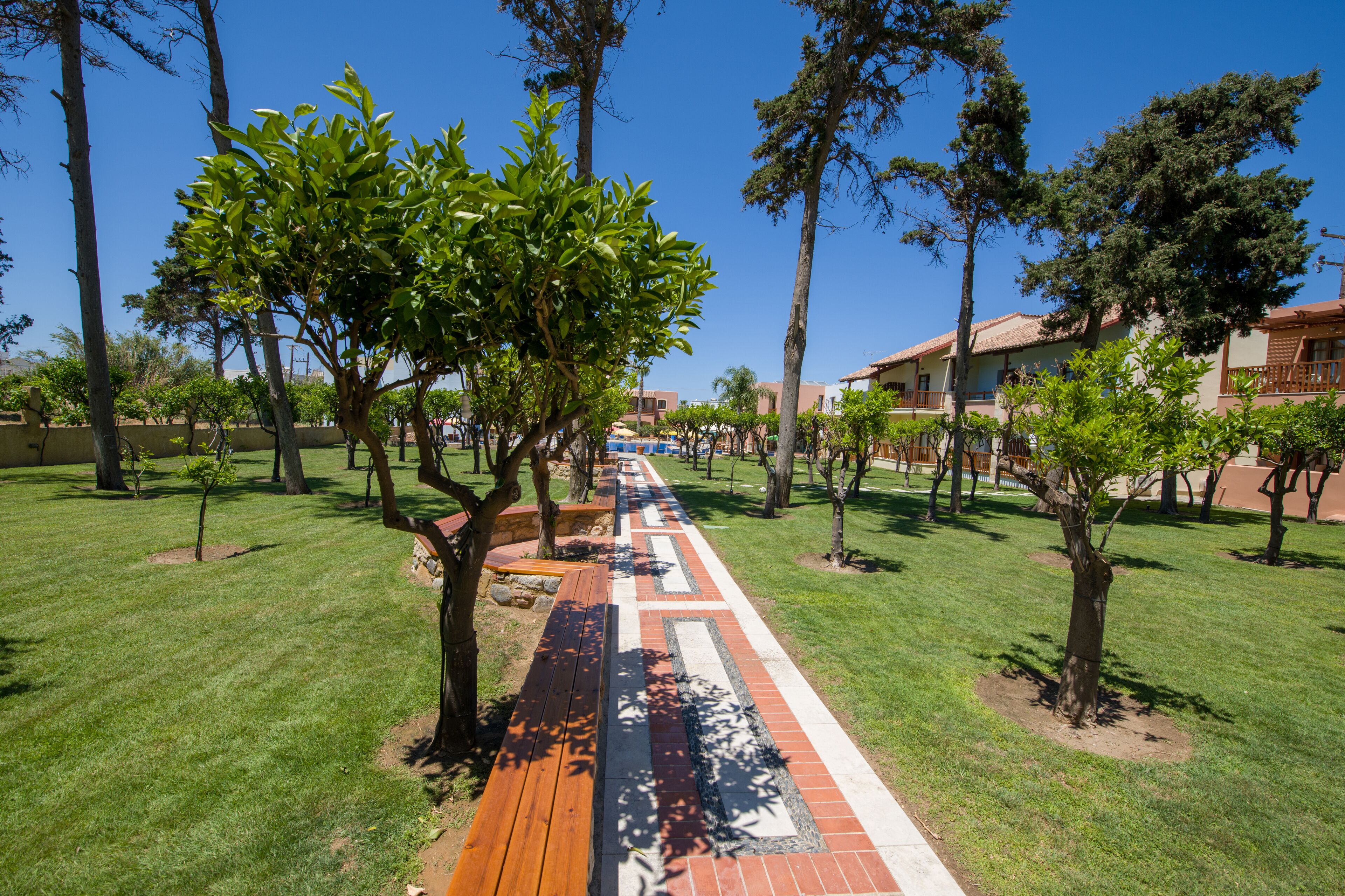 A pathway lined with trees and a brick walkway, leading to a building with a tiled roof.