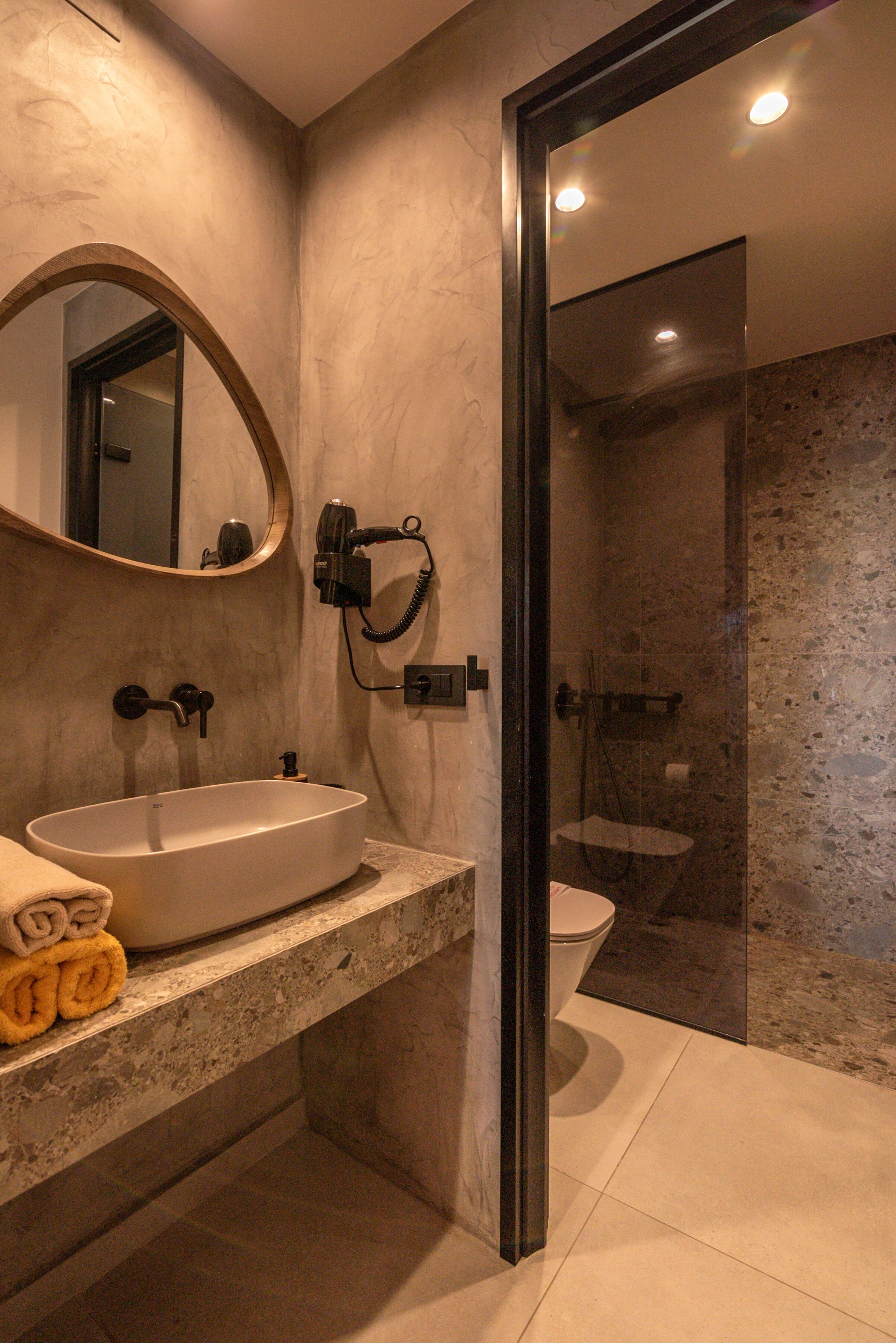 A modern bathroom with a marble sink, a glass-enclosed shower, and a large mirror.
