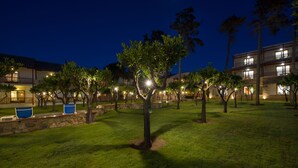 Un patio bien iluminado con árboles y una zona de piscina por la noche.