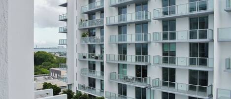 A modern multi-story building with balconies, a swimming pool, and a view of the cityscape.