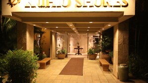 A hotel entrance with a sign reading "Hotel Suites," featuring a tiled floor, potted plants, and benches. - Ocean Front Condo with AC, enjoy the ocean from your own private lanai. (Koloa)