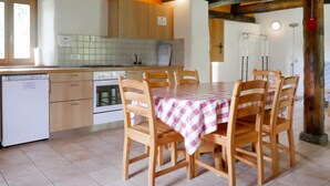 A cozy kitchen with wooden cabinets, a tiled backsplash, a dining table with chairs, and a built-in oven. - Rustico Dolomia by Interhome (Olivone)