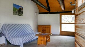 A cozy room with a wooden ceiling, a sofa with a striped blanket, a wooden table, and a window with a view of the outdoors. - Rustico Dolomia by Interhome (Olivone)