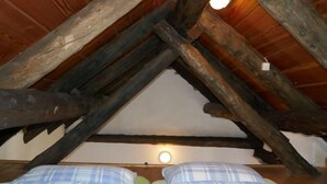 Ein Zimmer mit schrägem Holzboden und einem Bett mit Karomuster-Bettwäsche.