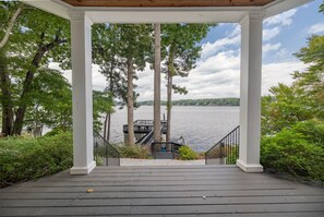 A covered wooden deck with white columns, leading to a dock over water.