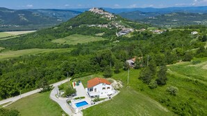 A white villa with a red roof, a swimming pool, and a view of a hill with a castle. - Montebello by Interhome (Motovun)