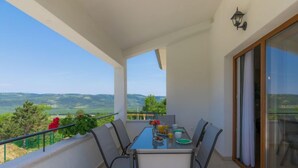 A balcony with a table set for breakfast, a view of the countryside, and a sliding glass door. - Montebello by Interhome (Motovun)