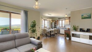 A modern living room with a sofa, a dining area with chairs, a kitchen with cabinets, and a balcony with a view. - Montebello by Interhome (Motovun)