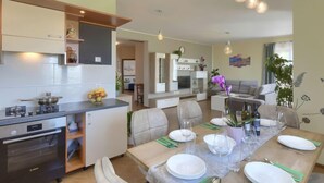 A modern kitchen with a dining area, a sofa, and a dining table set for six. - Montebello by Interhome (Motovun)