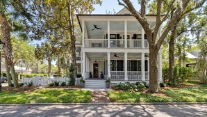 A two-story house with a porch, a white picket fence, and a well-maintained lawn.