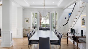 A spacious dining area with a long table, black chairs, and a chandelier.