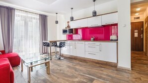 Eine moderne Küche mit weißen Schränken, einer roten Spritzschutzwand und einem Glastisch mit vier Stühlen.