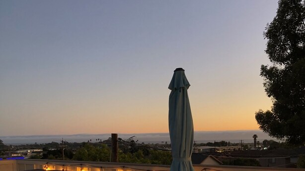 A rooftop patio with outdoor seating, a fire feature, and a view of the city skyline at dusk. - Family friendly Grover Beach house located blocks from the ocean.    (Grover Beach)