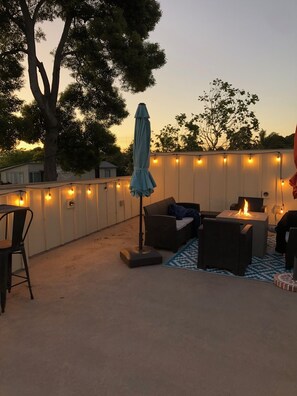 An outdoor patio area with a fire pit, seating, and string lights. - Family friendly Grover Beach house located blocks from the ocean.    (Grover Beach)