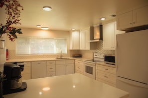 A modern kitchen with white cabinetry, a stainless steel refrigerator, and a built-in microwave. - Private Seattle Getaway Home Near Lake Washington! (Seattle)