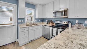 A kitchen with white cabinets, a stainless steel stove, a microwave, and a toaster.
