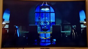 Ein Fernsehbild zeigt einen dunklen Raum mit einem großen Bogenfenster, einer Chandelier und zwei Sesseln.