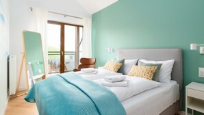 A bedroom with a bed, a bedside table, a chair, a window, and a view of buildings outside.