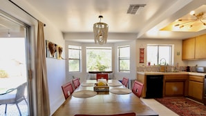 A spacious dining area with a large wooden table, red chairs, and a chandelier. - Relax Close to Park, Hot Tub, Hammocks, Private, Lush Trees (Joshua Tree)