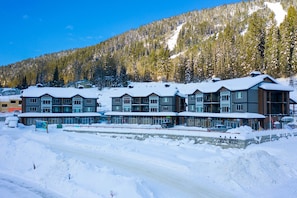A multi-story hotel with a ski slope in the background. - Townhome with Garage, 3 Bedrooms and Hot Tub (Sun Peaks)