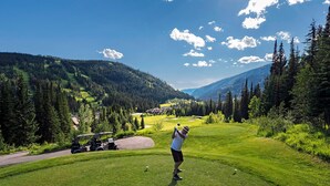A golf course with a clear view of the surrounding forest and mountains. - Townhome with Garage, 3 Bedrooms and Hot Tub (Sun Peaks)